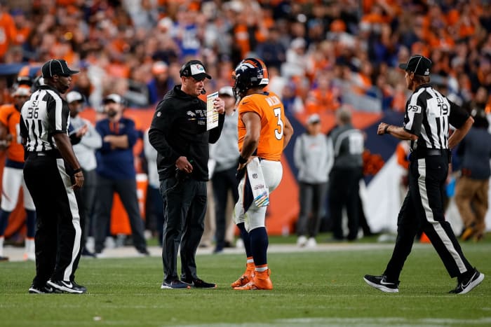 Denver Broncos head coach Nathaniel Hackett talks with quarterback Russell Wilson (3) as side judge Anthony Jeffries (36) and down judge Kent Payne (79) look on in the fourth quarter against the Indianapolis Colts at Empower Field at Mile High.